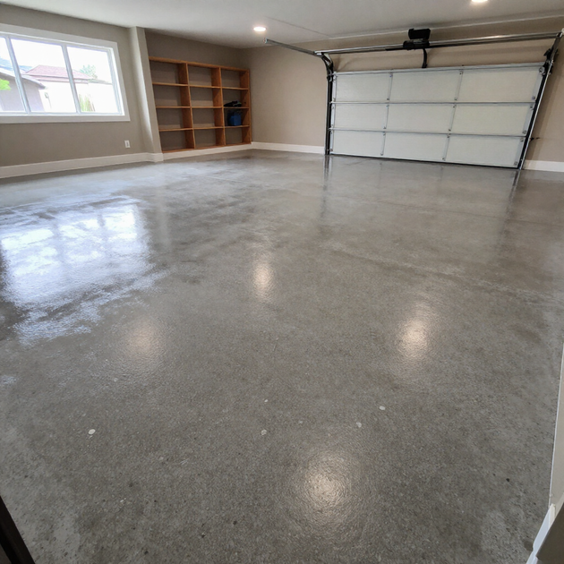 Empty garage with glossy gray floor, shelves along the wall, and a closed garage door.