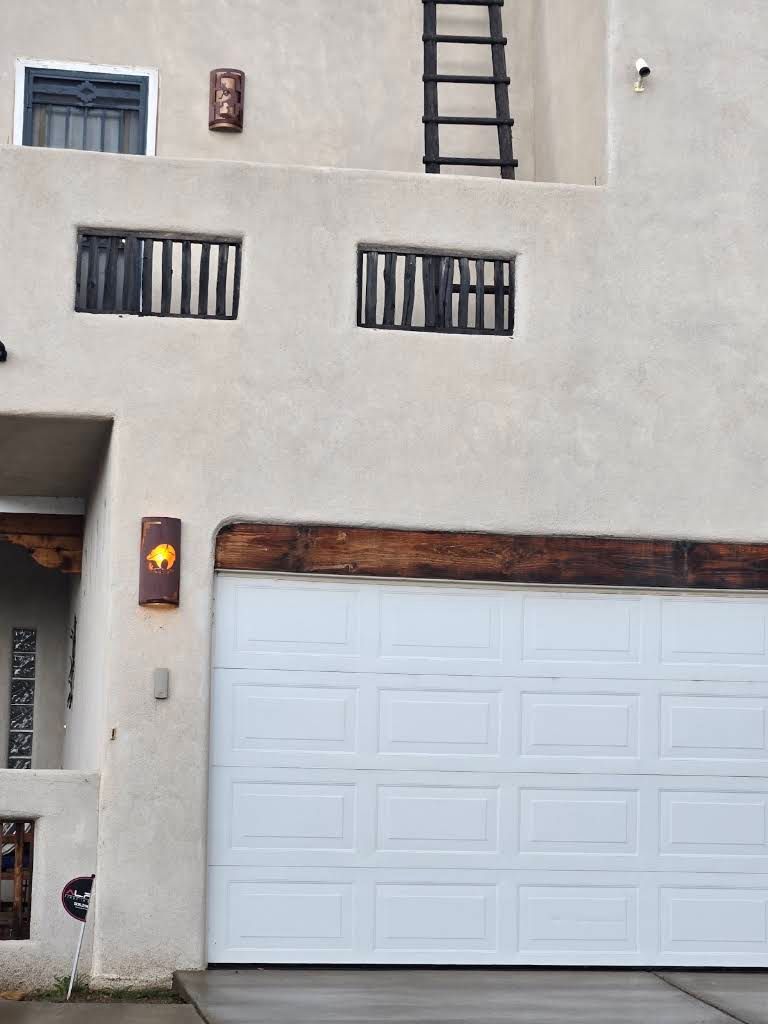Modern beige house facade with a white garage door and barred windows