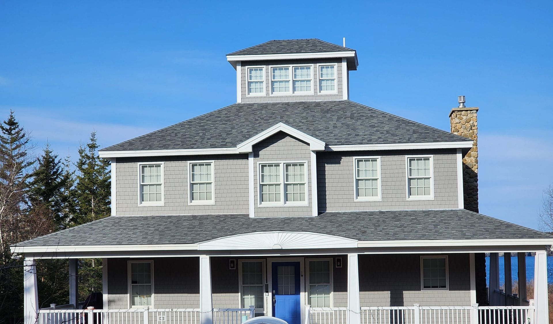 A large house with a blue door and a porch on a sunny day.