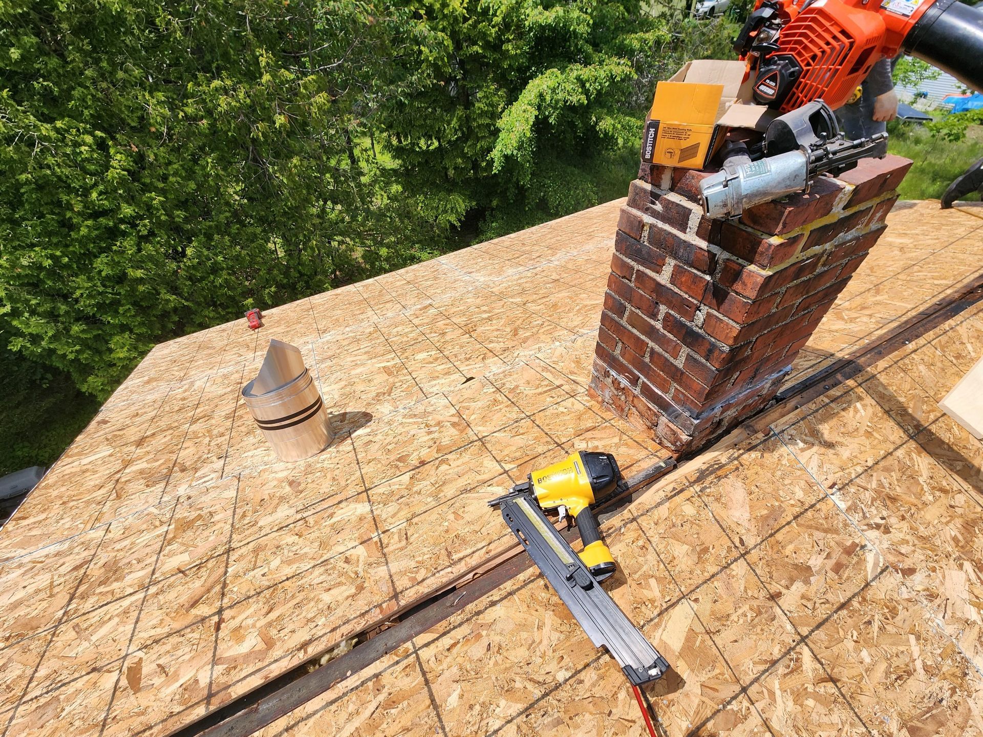 A roof with a chimney and tools on it.