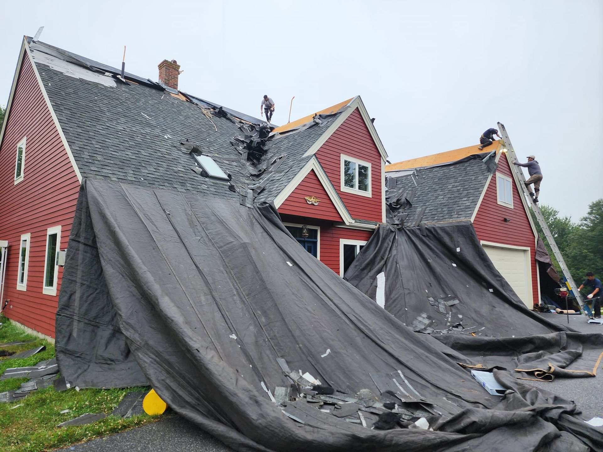 A red house with a black tarp on the ground in front of it.