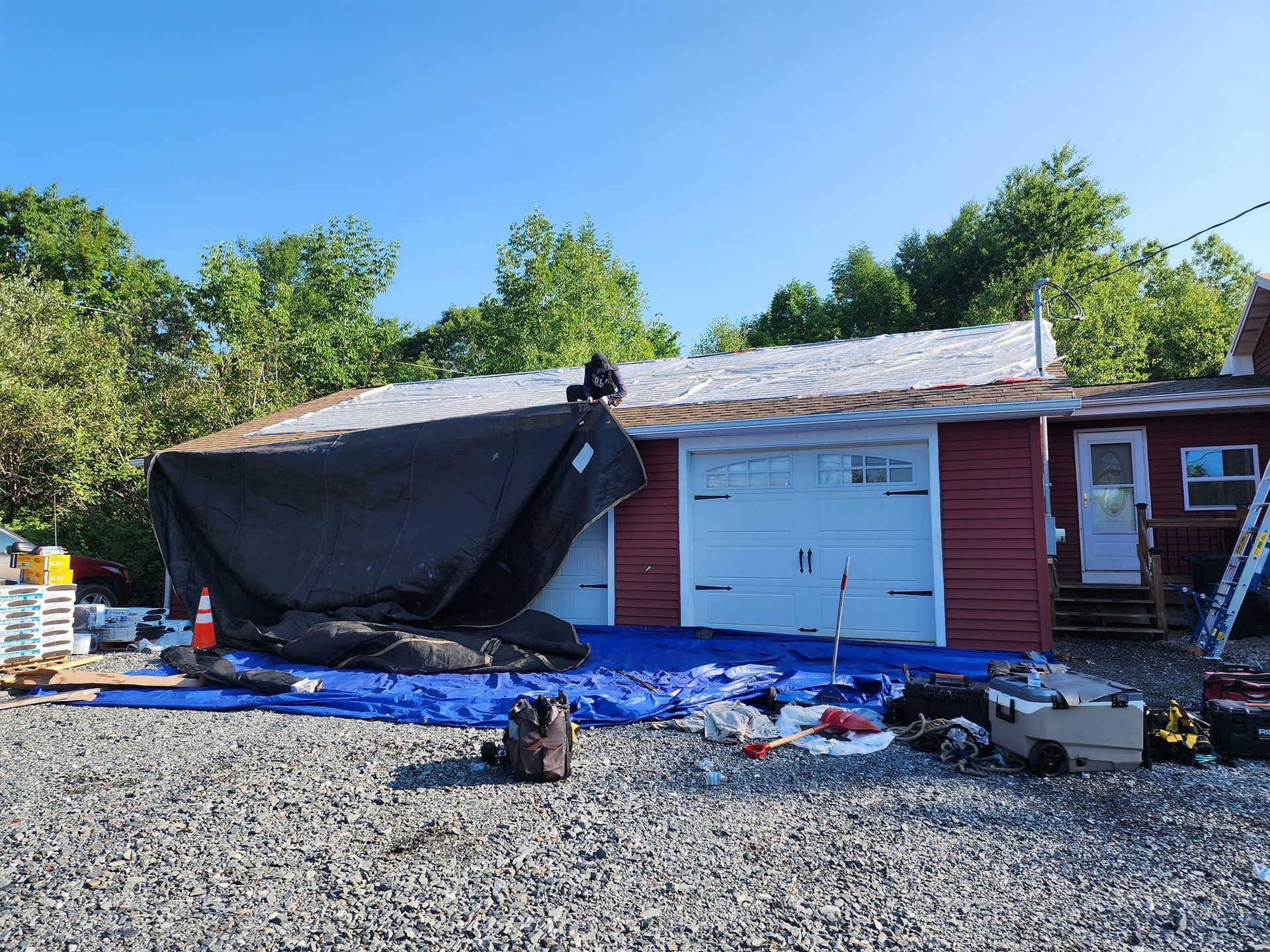 A red house with a white garage door is being painted