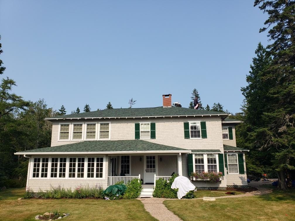 A large white house with green shutters on the windows