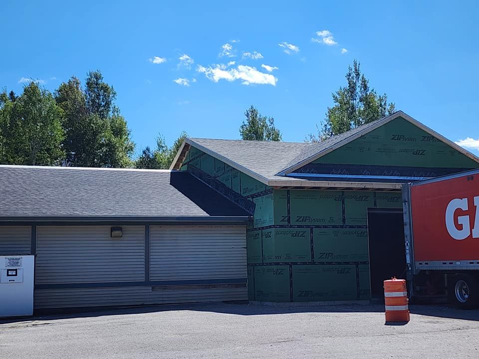 A red truck with the word gi on it is parked in front of a house under construction