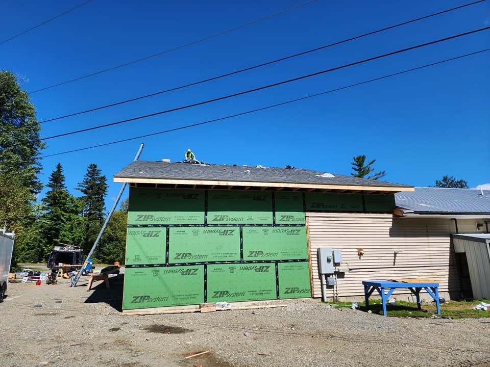 A house is being built with green siding and a roof.