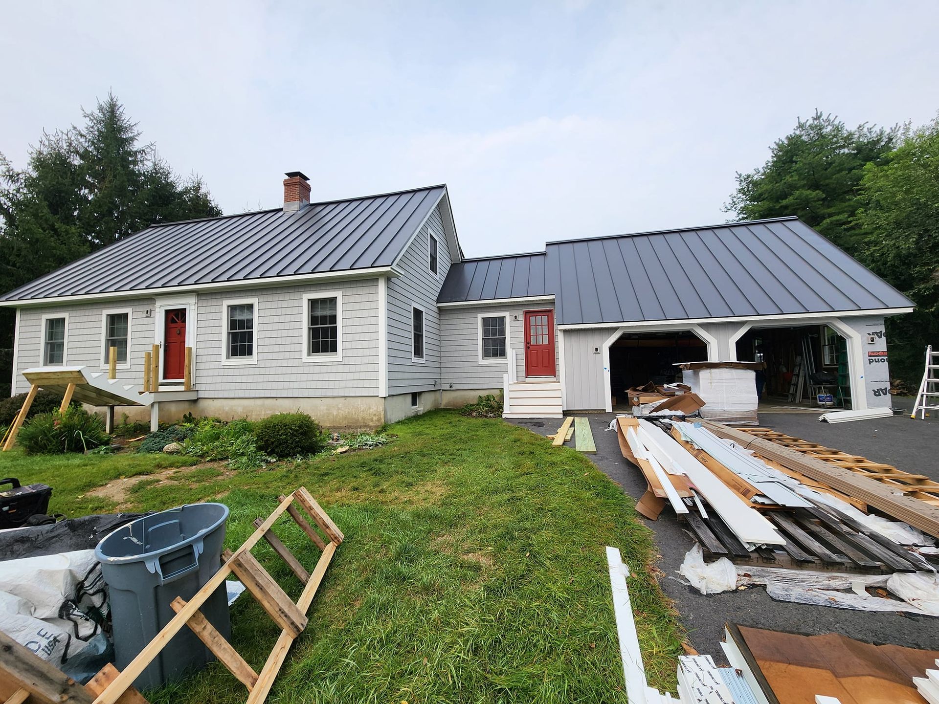 A white house with a metal roof is being remodeled.
