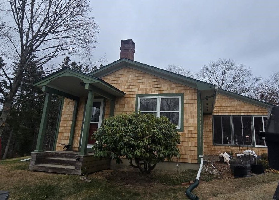 A house with a porch and a tree in front of it