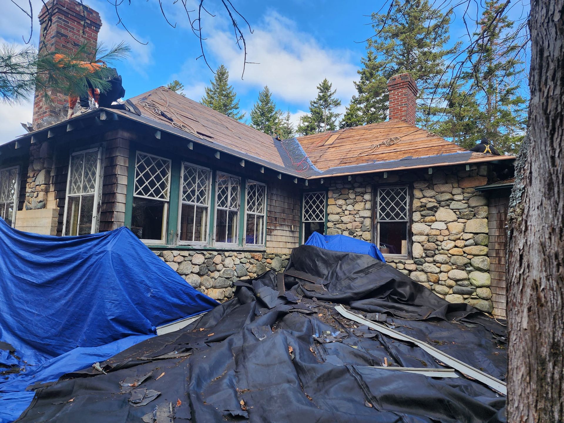 A large stone house with a blue tarp on the ground in front of it.
