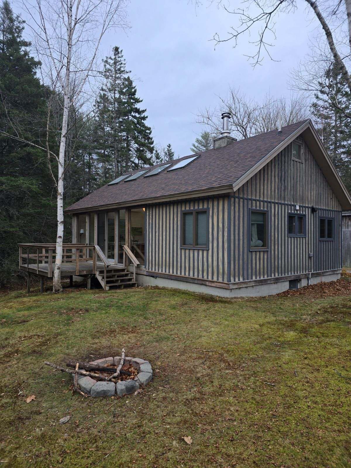 A small house with a fire pit in front of it in the woods.