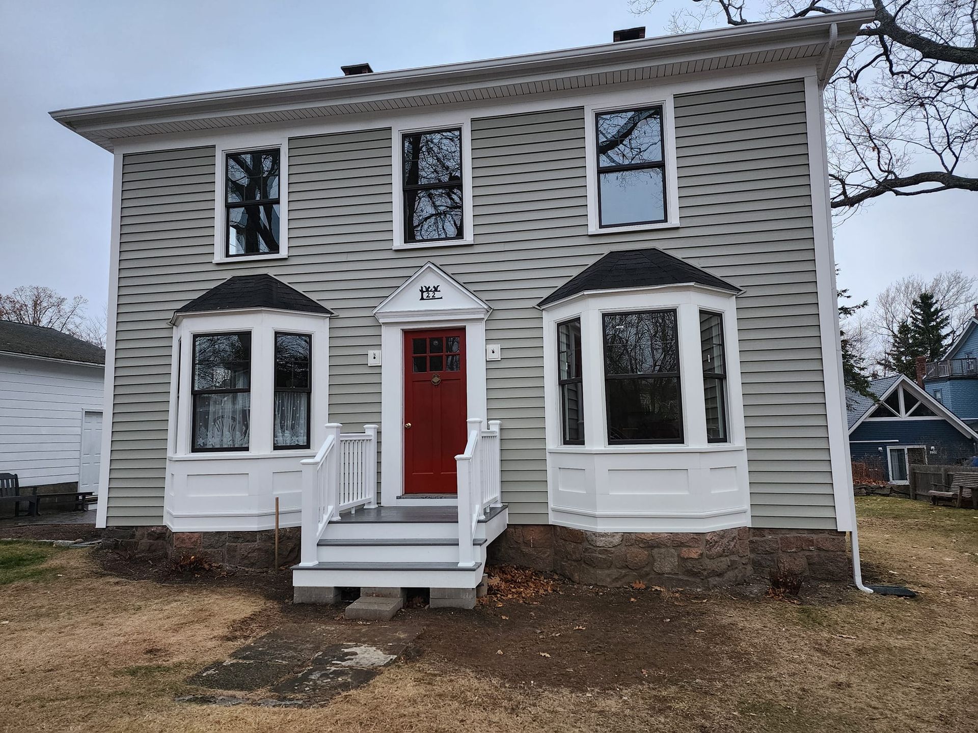 A large house with a red door and stairs in front of it.
