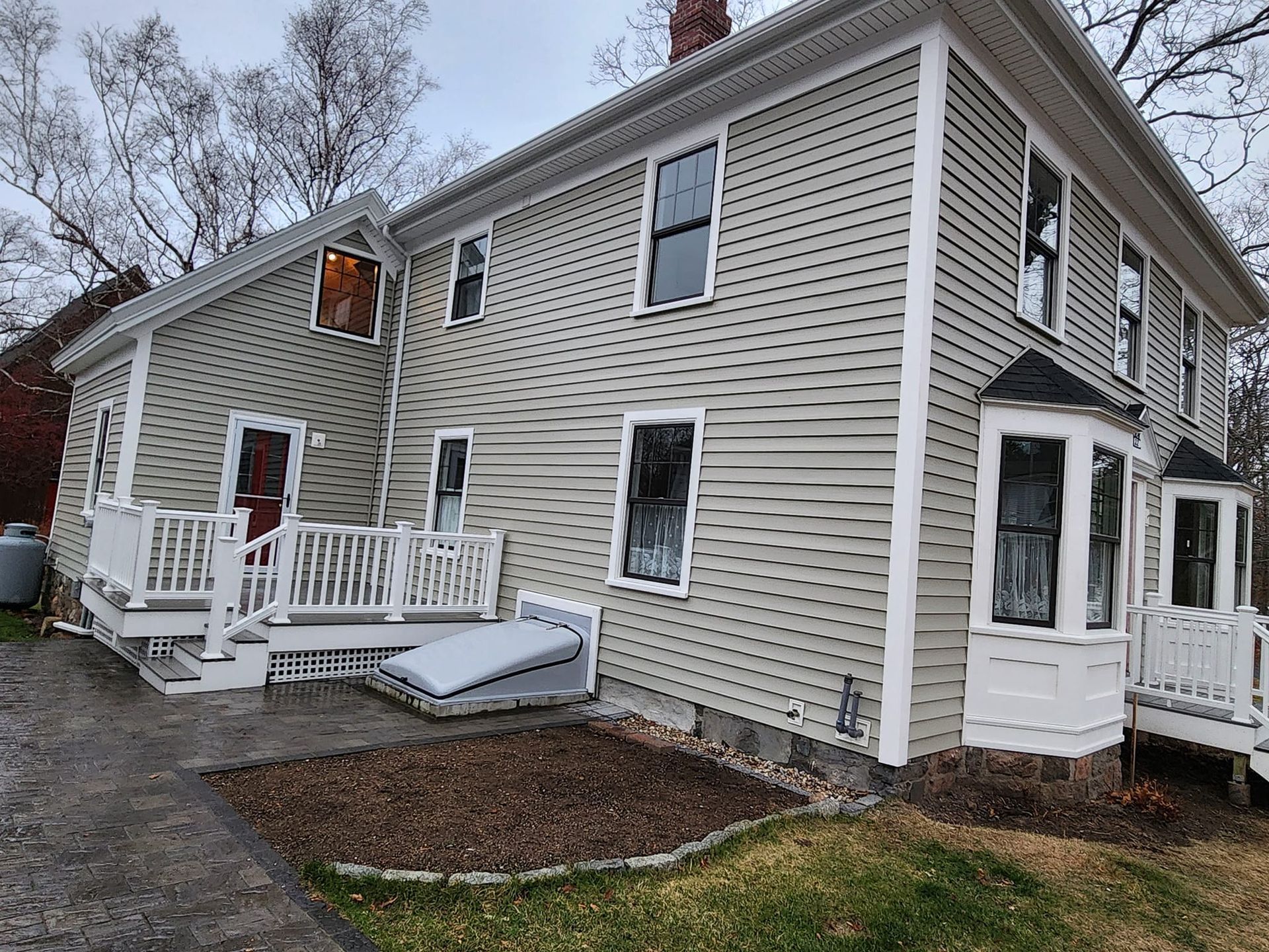 A large house with a white deck and stairs on the side of it.