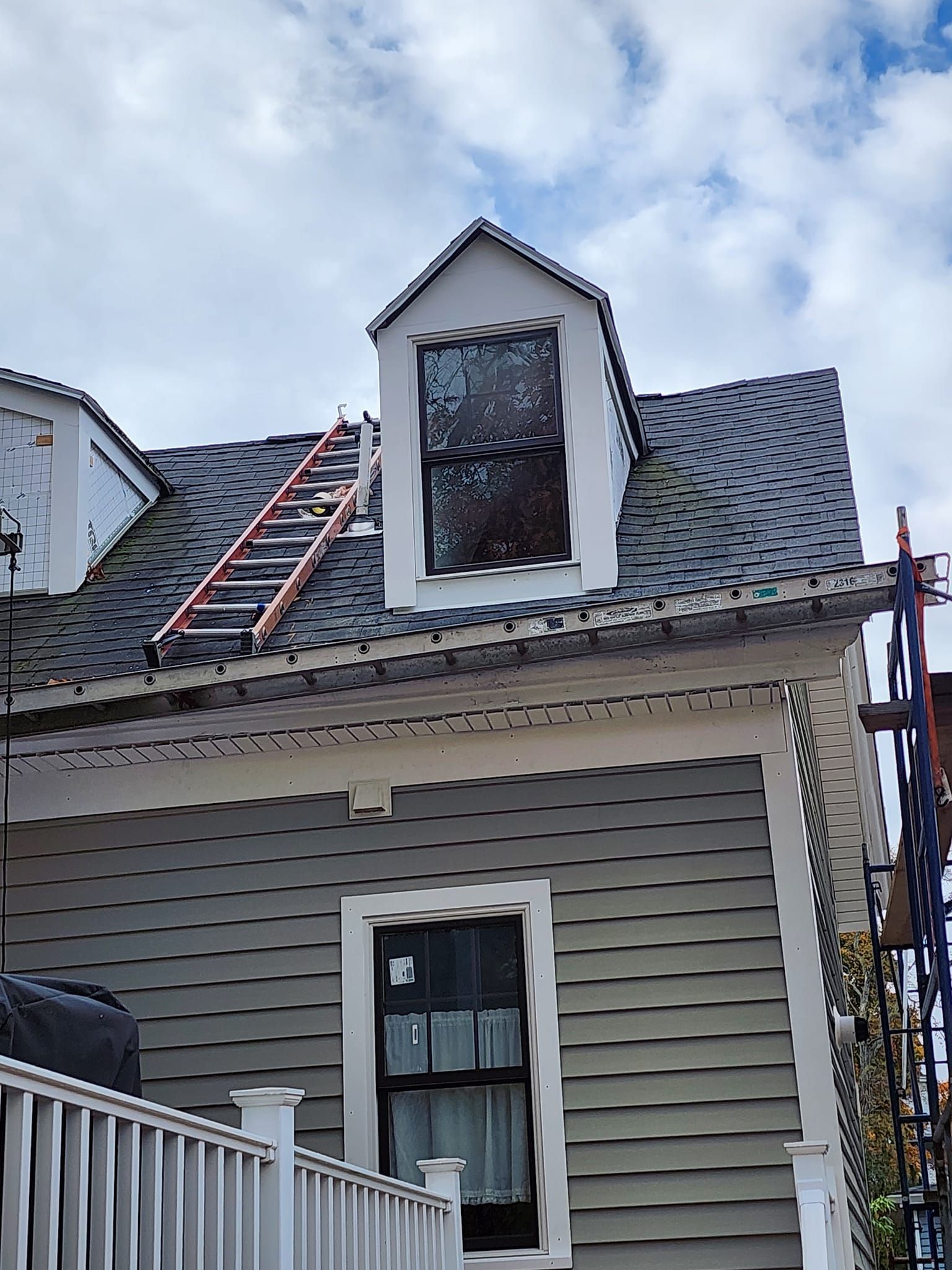 A house with a ladder on the roof and a window.