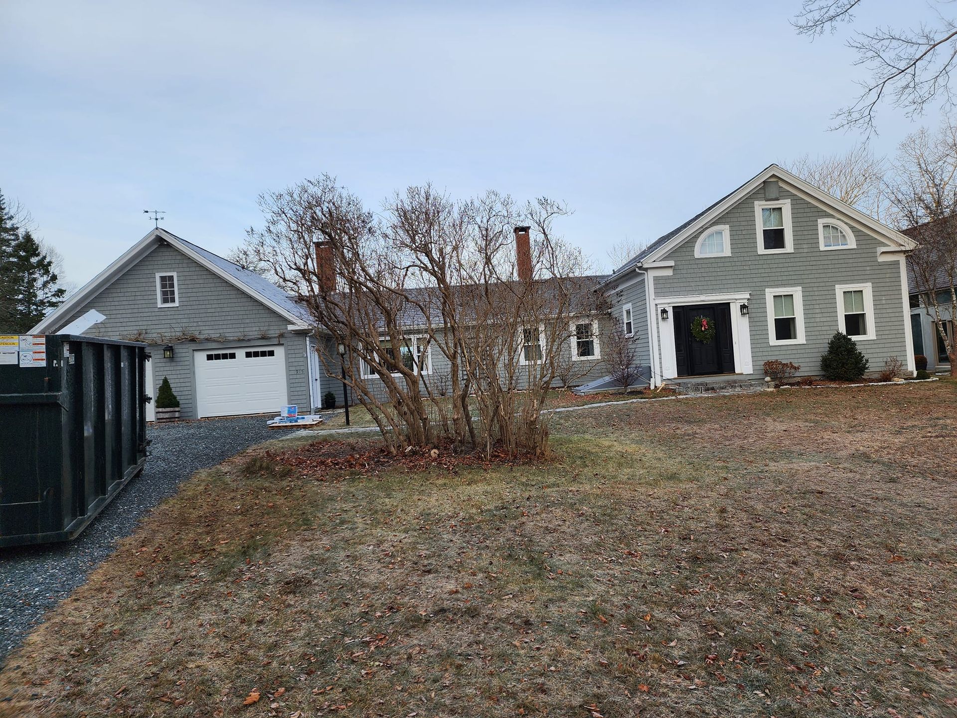 A large house with a garage and a smaller house in the background.