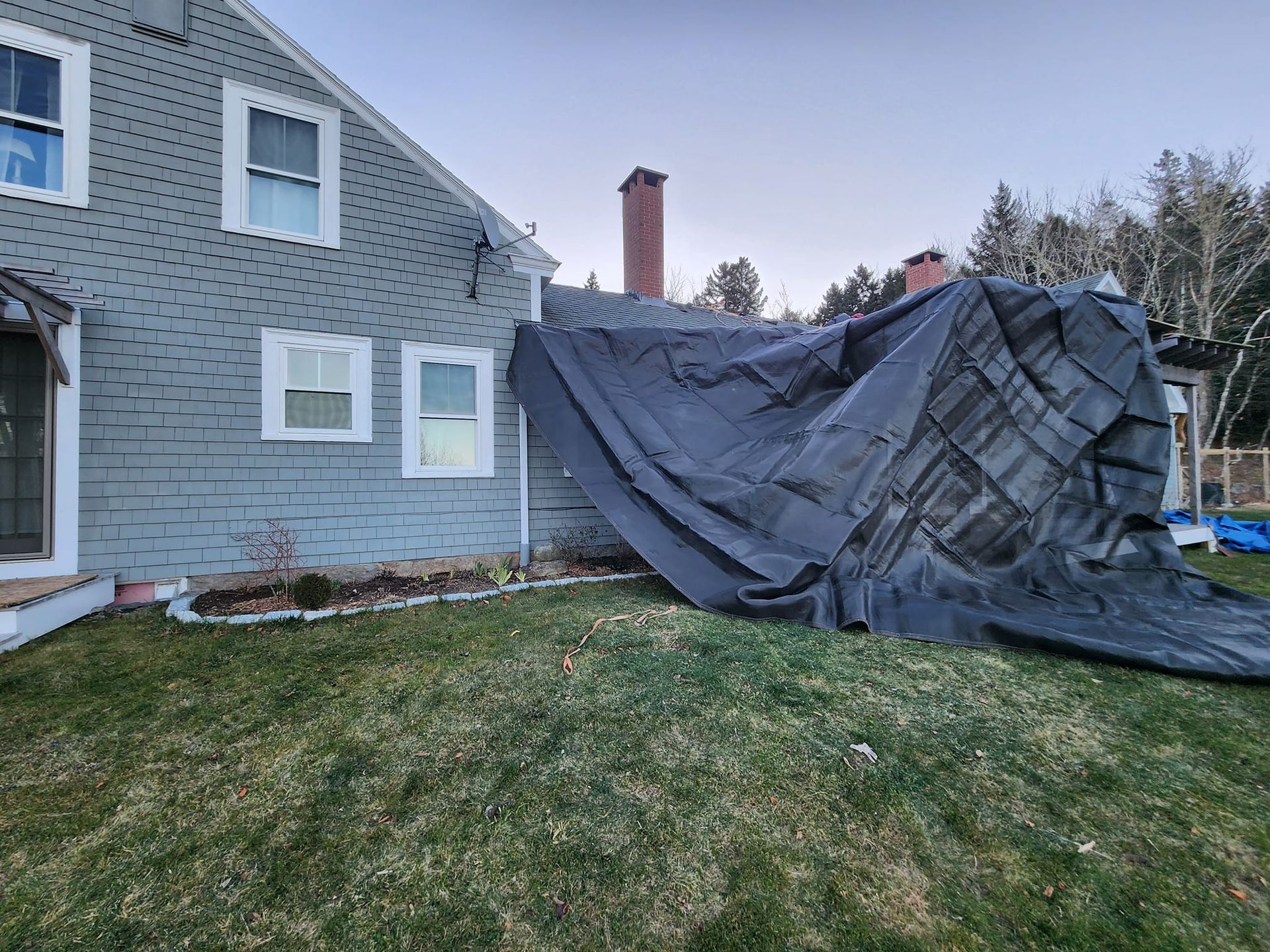 A large tarp is covering the roof of a house.