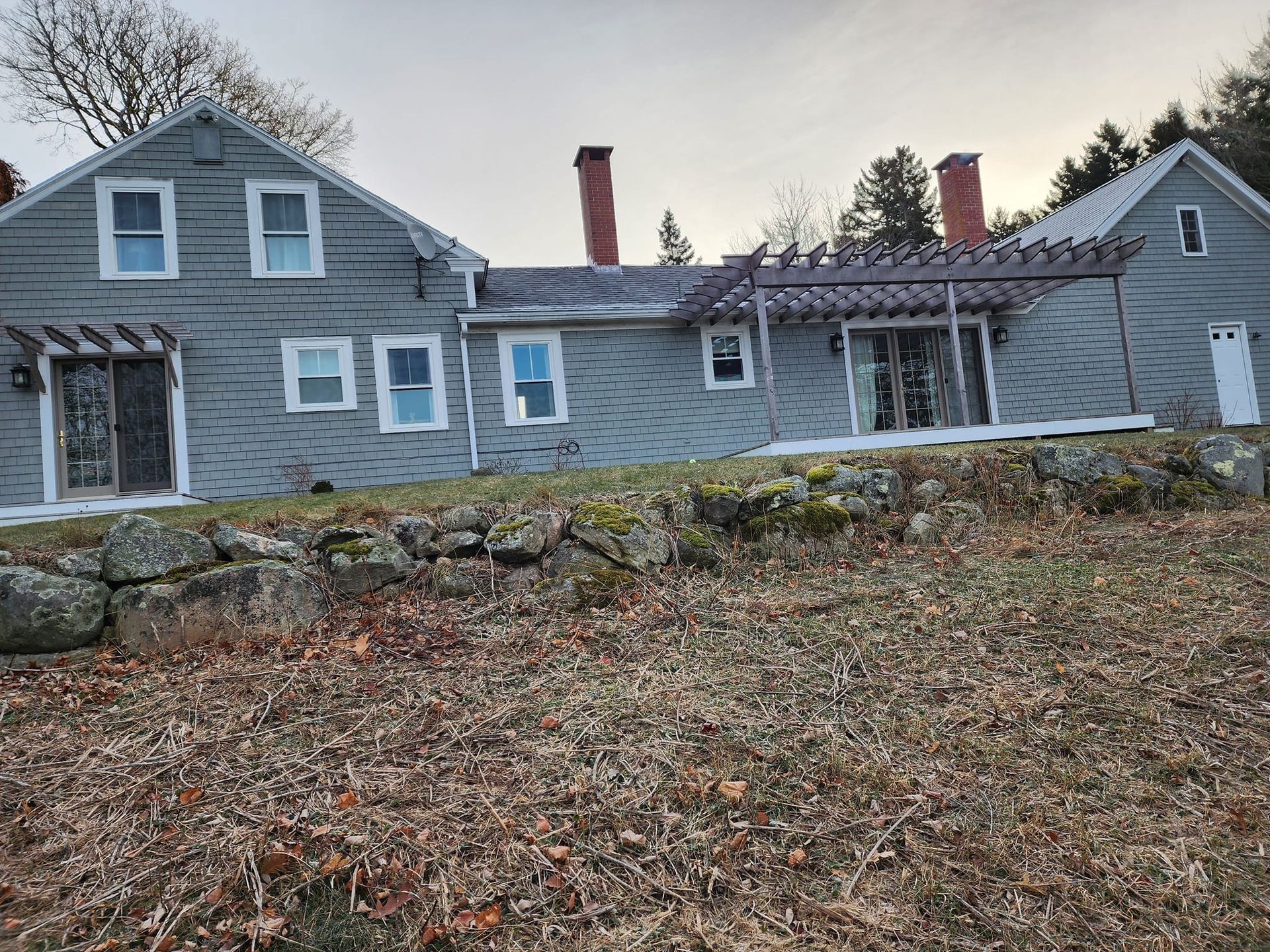 A large gray house is sitting on top of a hill.