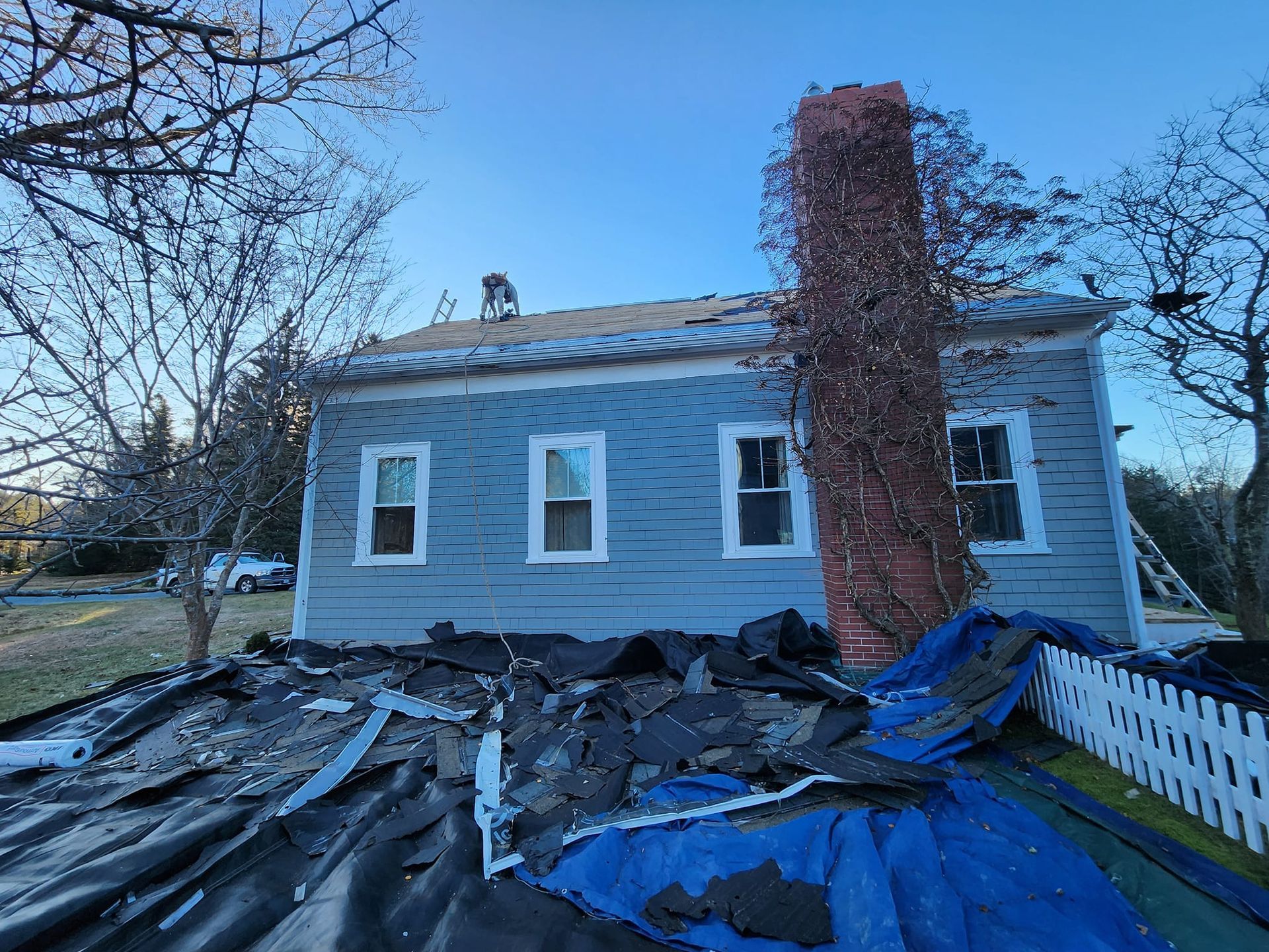 A house with a roof that is being removed and a chimney.