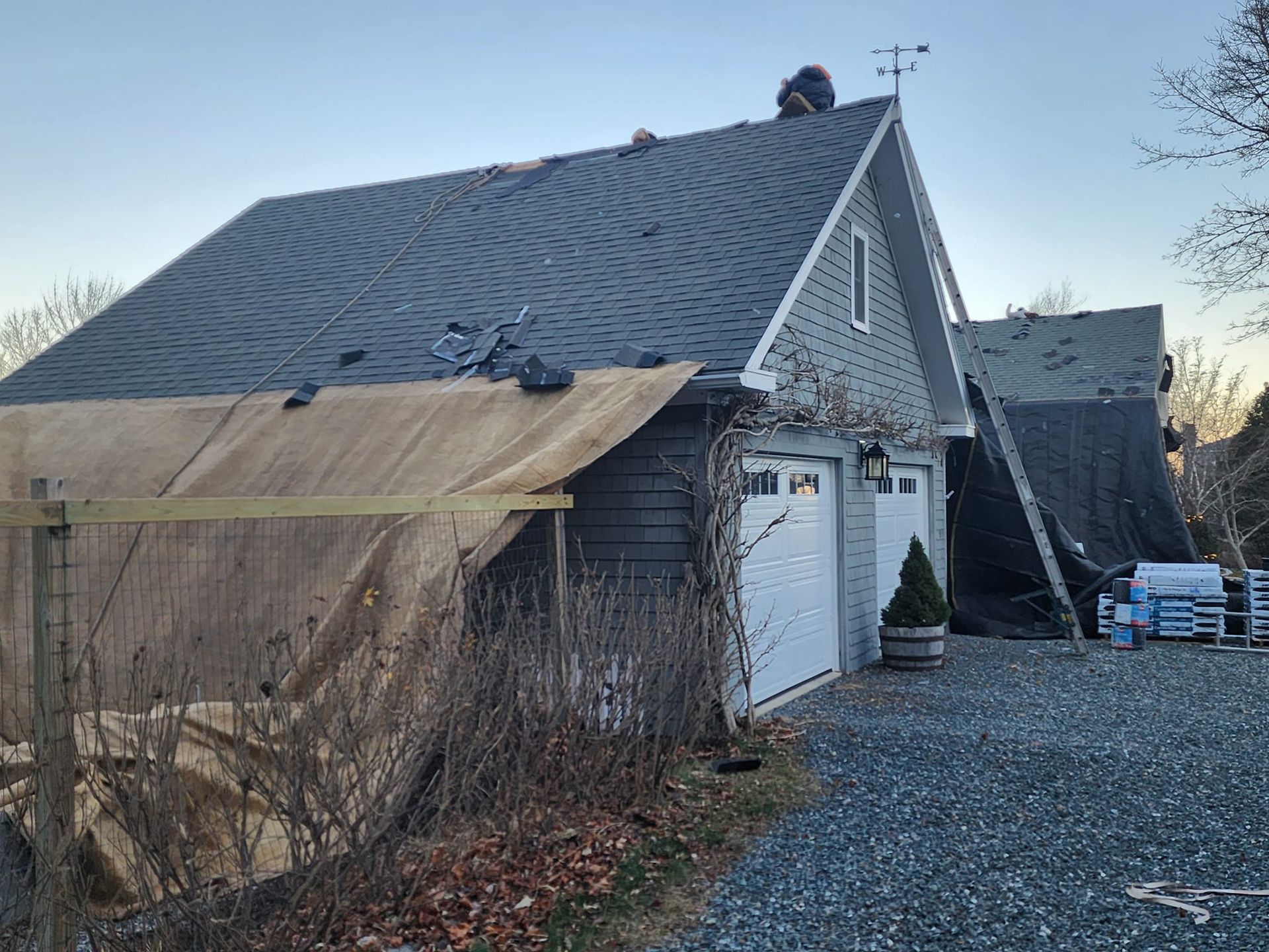 A roof is being installed on a house next to a garage.