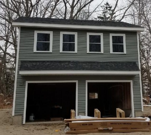 A garage under construction with a stack of lumber in front of it