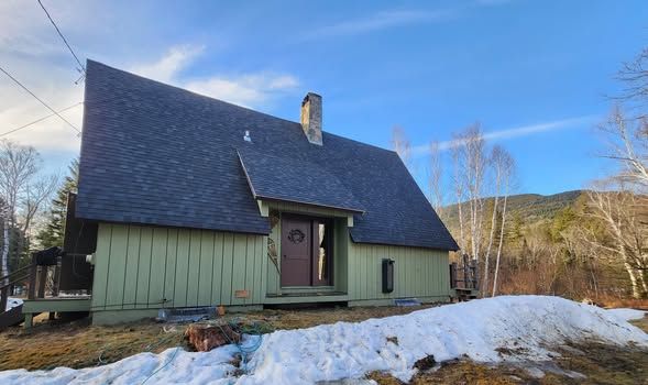 A green house with a black roof is sitting on top of a snow covered field.