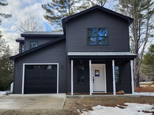A black house with a garage and a porch.