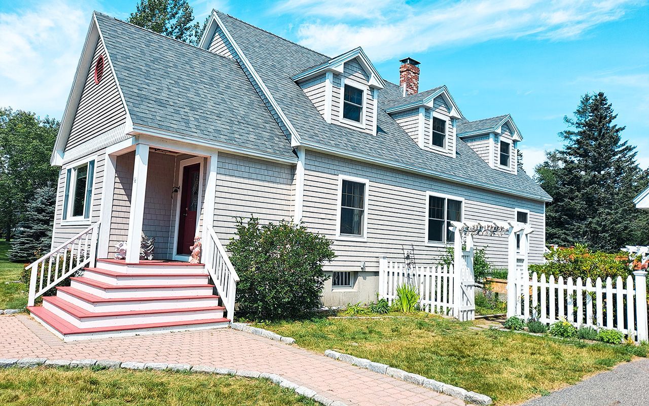 A large white house with a blue roof and a white picket fence.