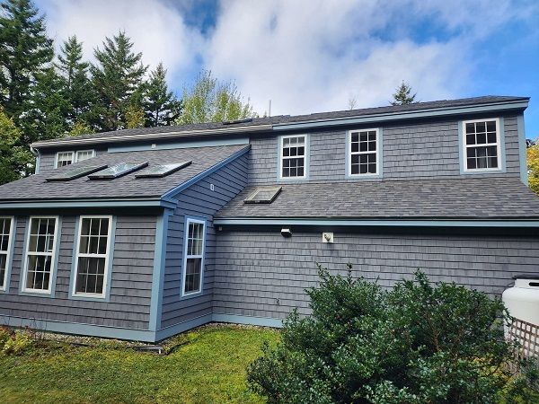 A large gray house with a lot of windows and a skylight on the roof.