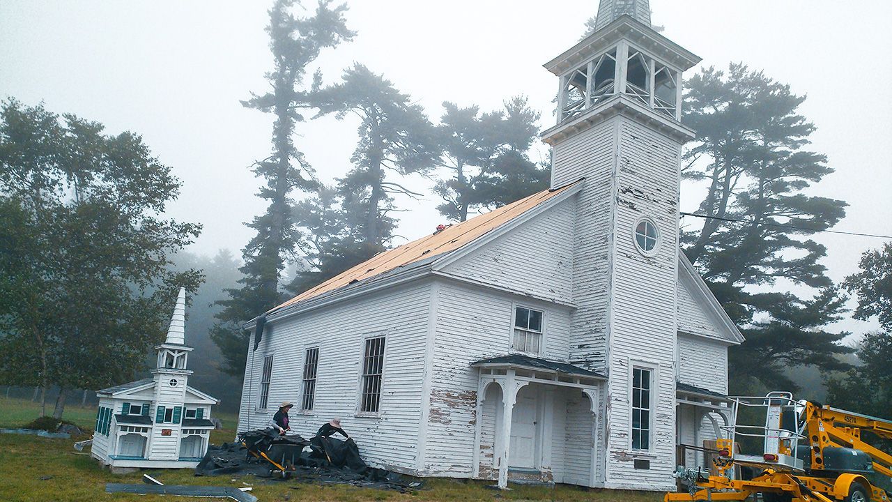 A white church is being restored on a foggy day