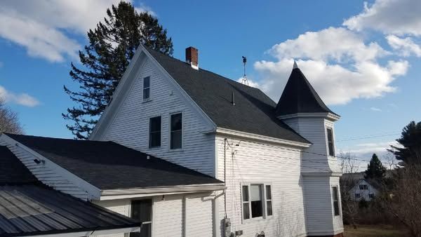 A white house with a black roof and a tower on top