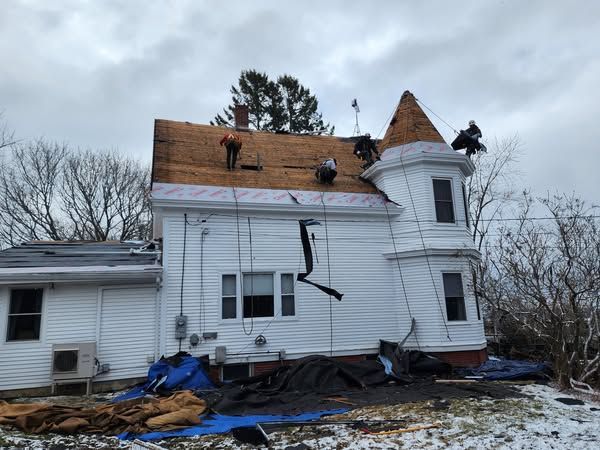 A white house with a roof that is being repaired