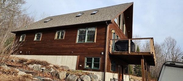 A large wooden house with a large deck on the side of it.