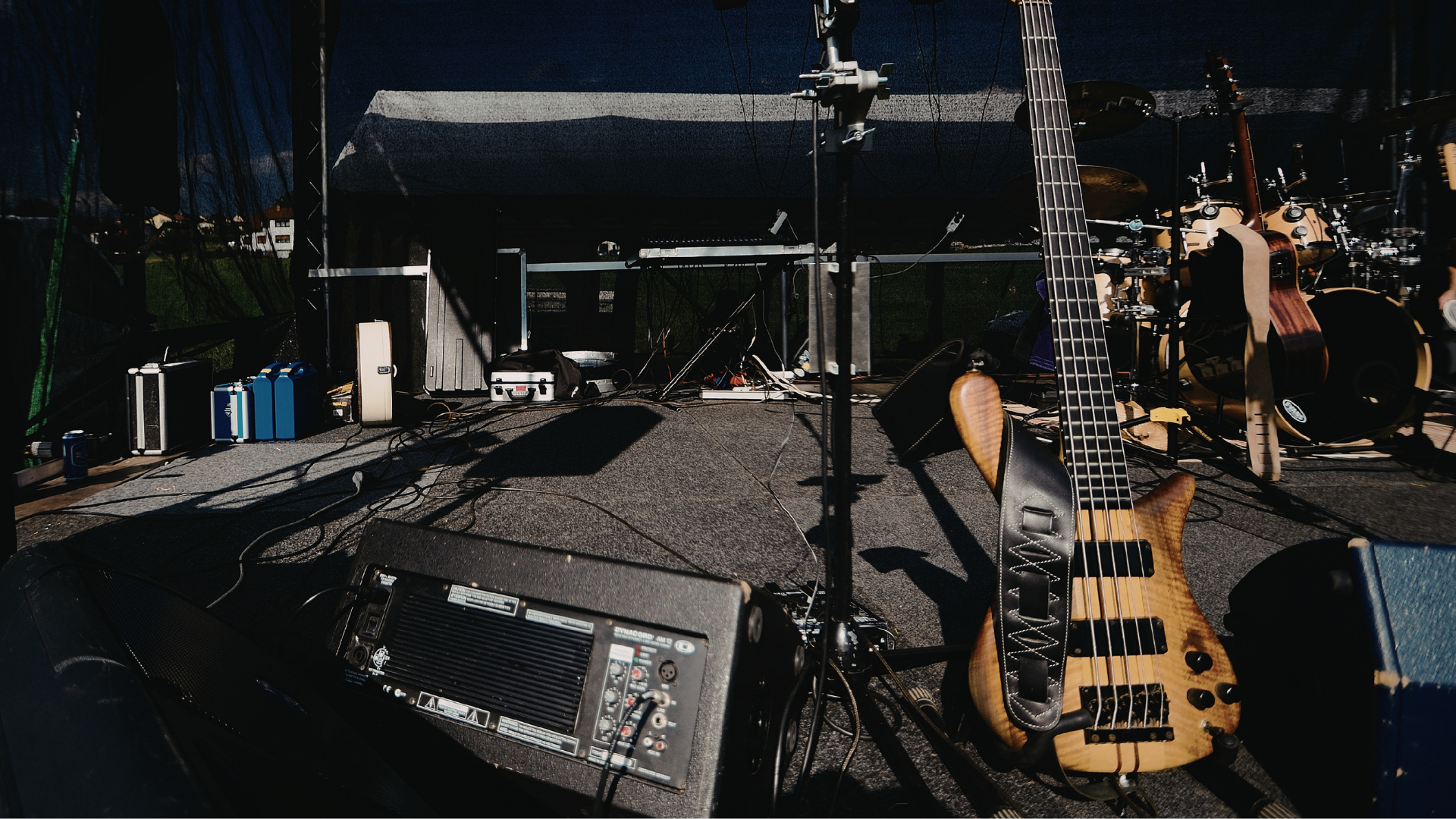 Dimly lit stage with guitars, microphone stands, and equipment set up for a concert