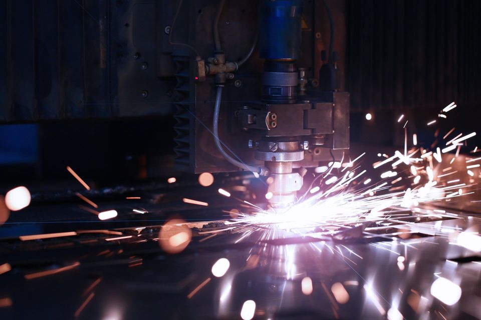 Une machine coupe un morceau de métal et des étincelles en sortent.