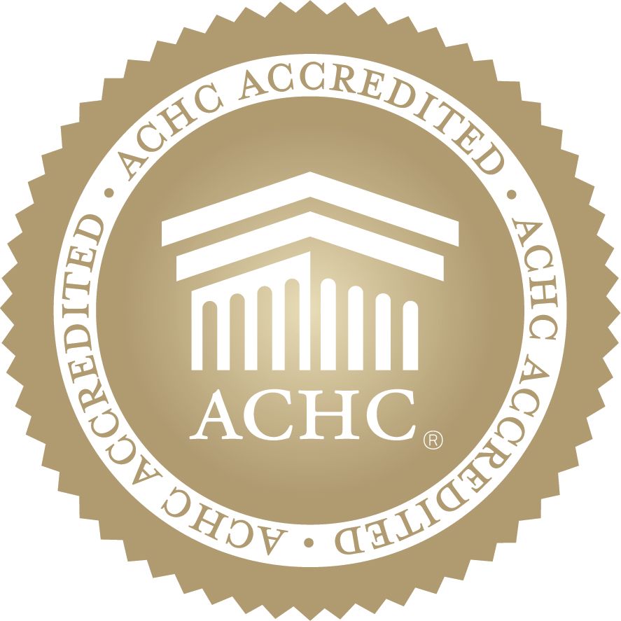 A round, gold-colored ACHC Accredited seal featuring a building icon above the text