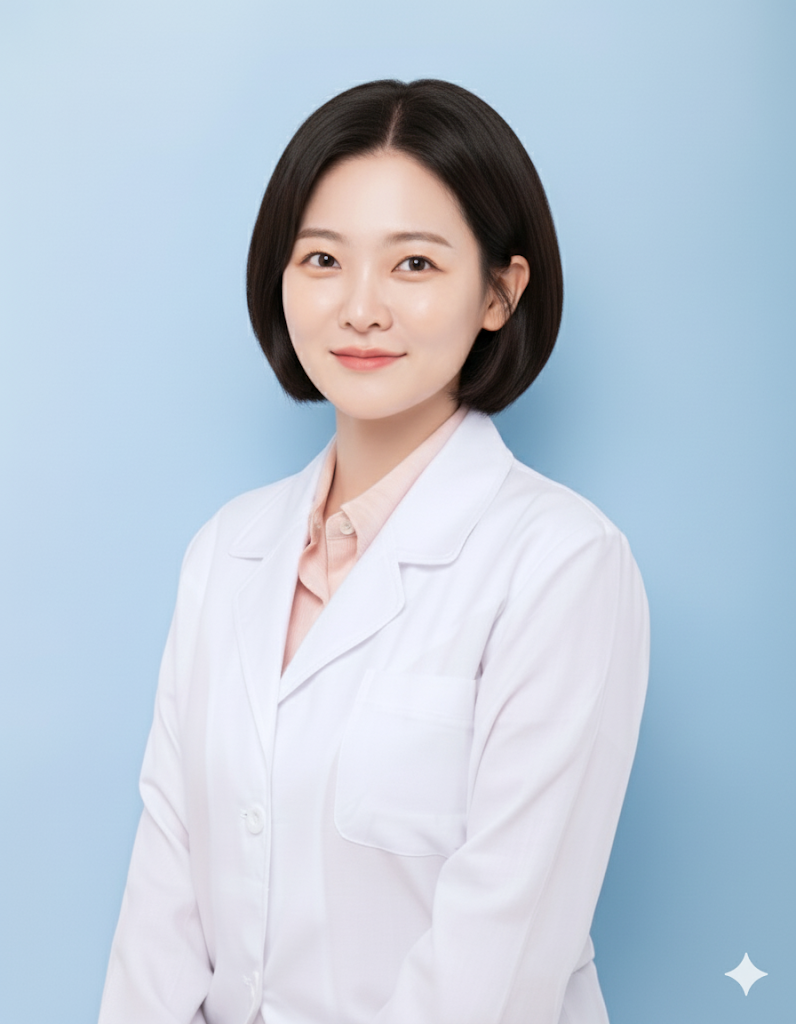 A person with short dark hair wearing a white lab coat over a light-colored shirt, posed against a solid blue background.