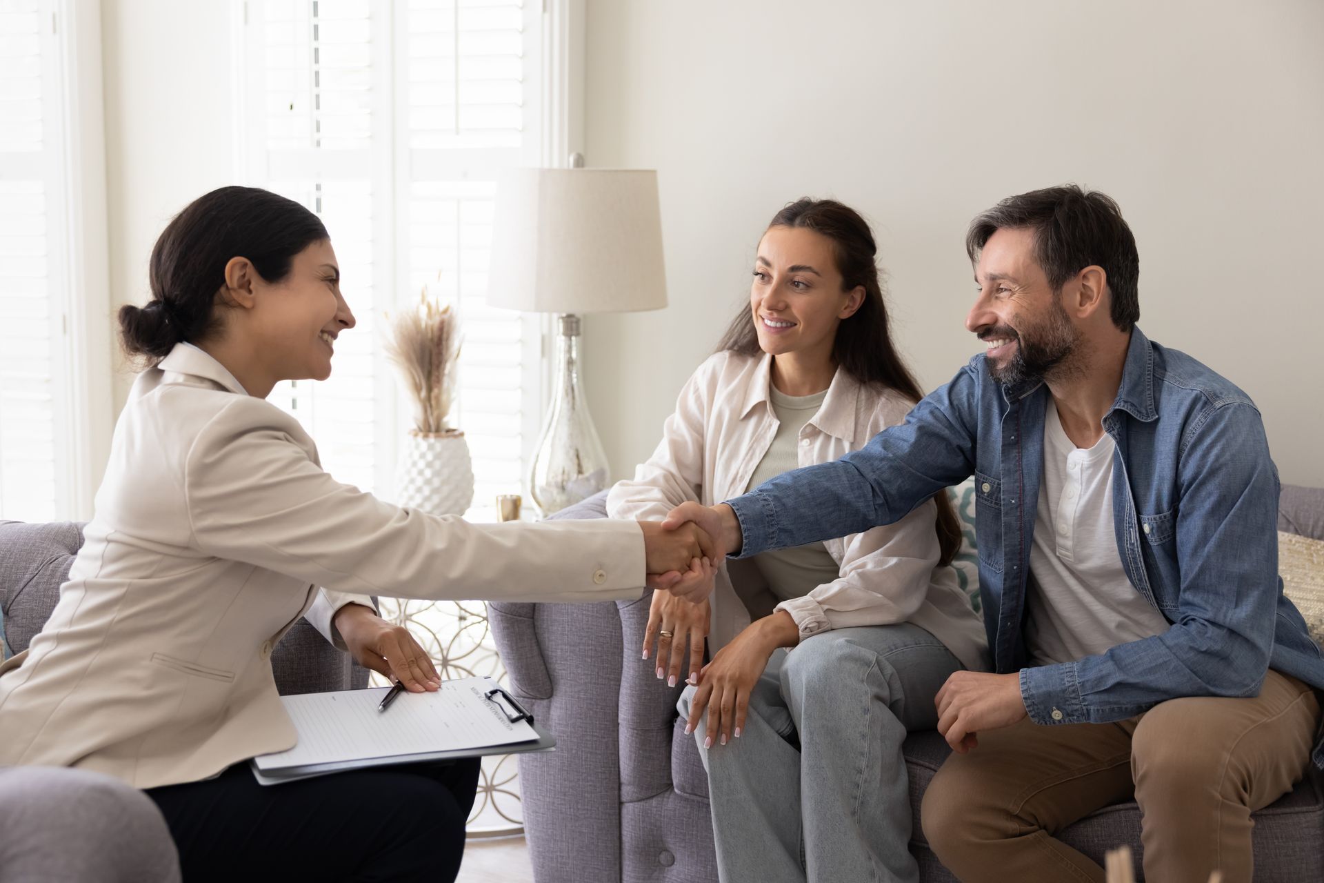 Three people in a living room shaking hands during a friendly meeting