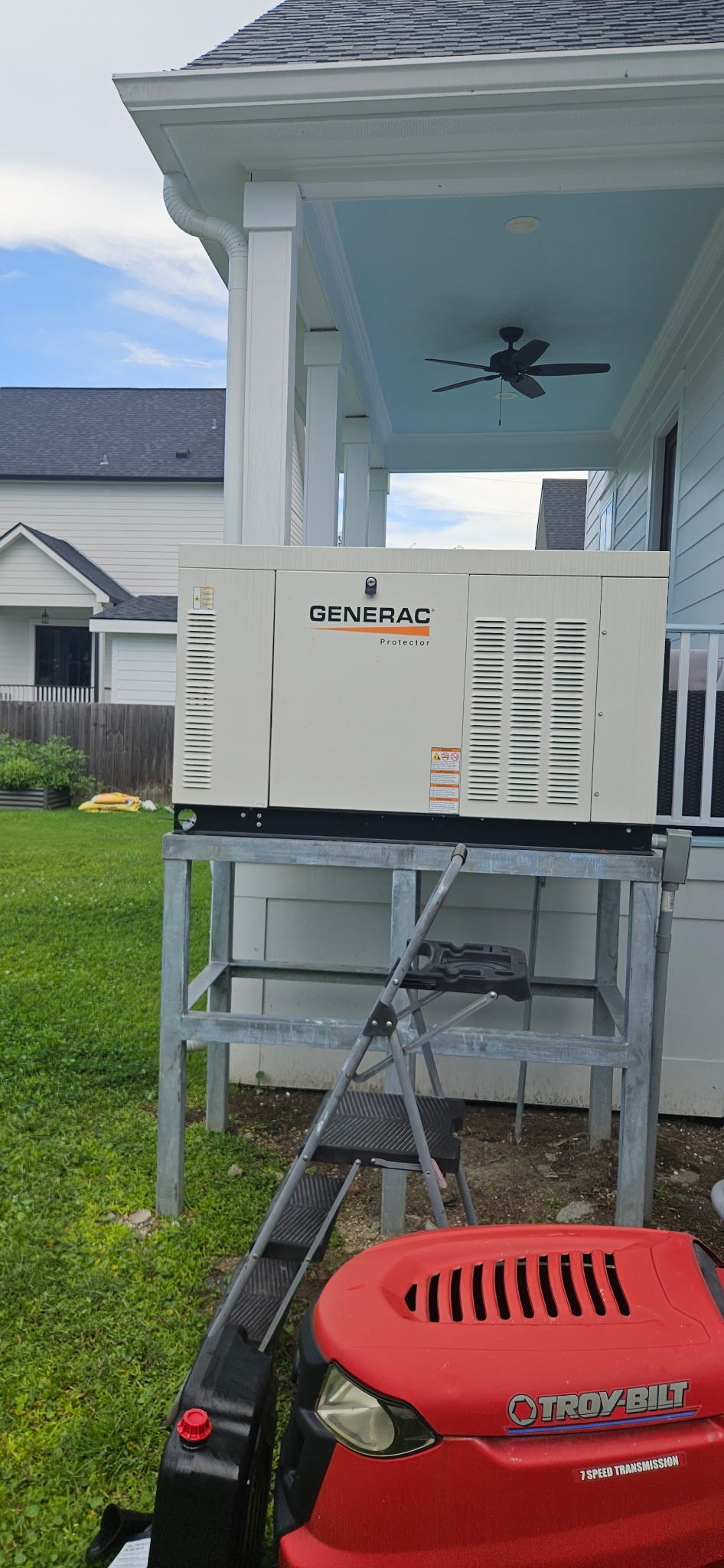 Outdoor electrical panel with exposed wiring and an EV charger mounted on a yellow-sided building.