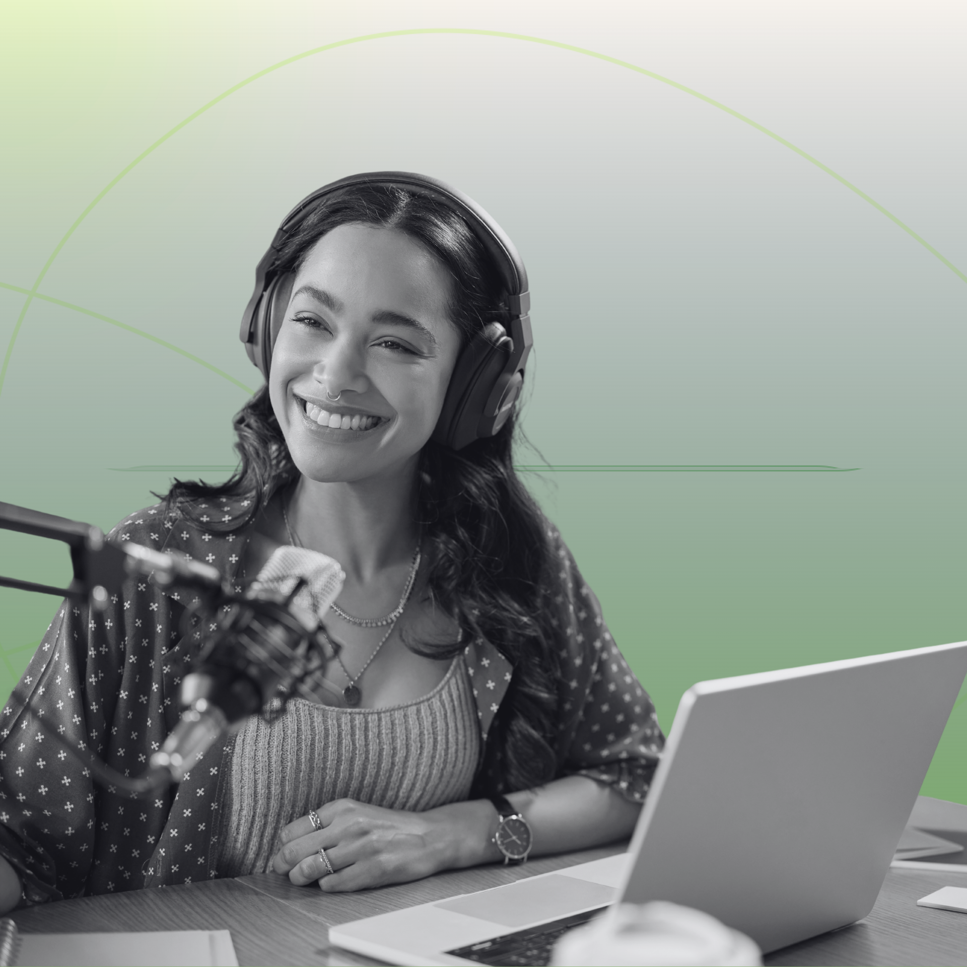 El presentador del podcast, sonriente y con auriculares puestos, habla por un micrófono situado junto a un portátil abierto.
