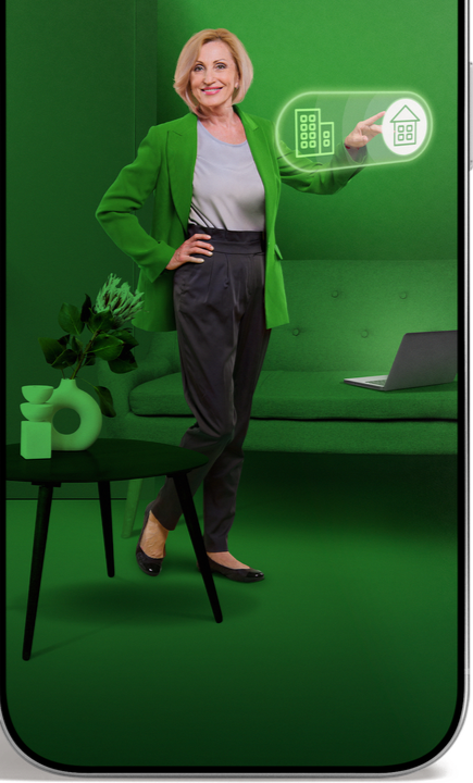 Mujer rubia con blazer verde de pie en un estudio verde junto a un portátil e iconos de finanzas digitales.