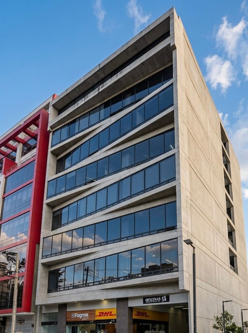 Edificio de oficinas moderno de varias plantas con ventanas azules reflectantes y fachada beige en una calle de la ciudad.