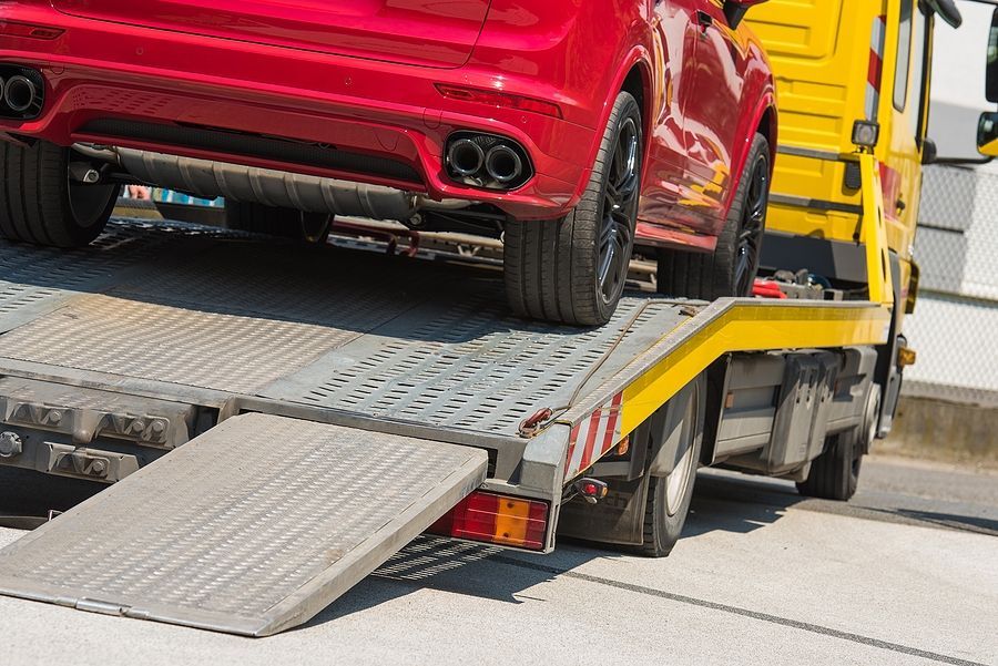 Rear view of a red luxury car being transported on a flatbed.