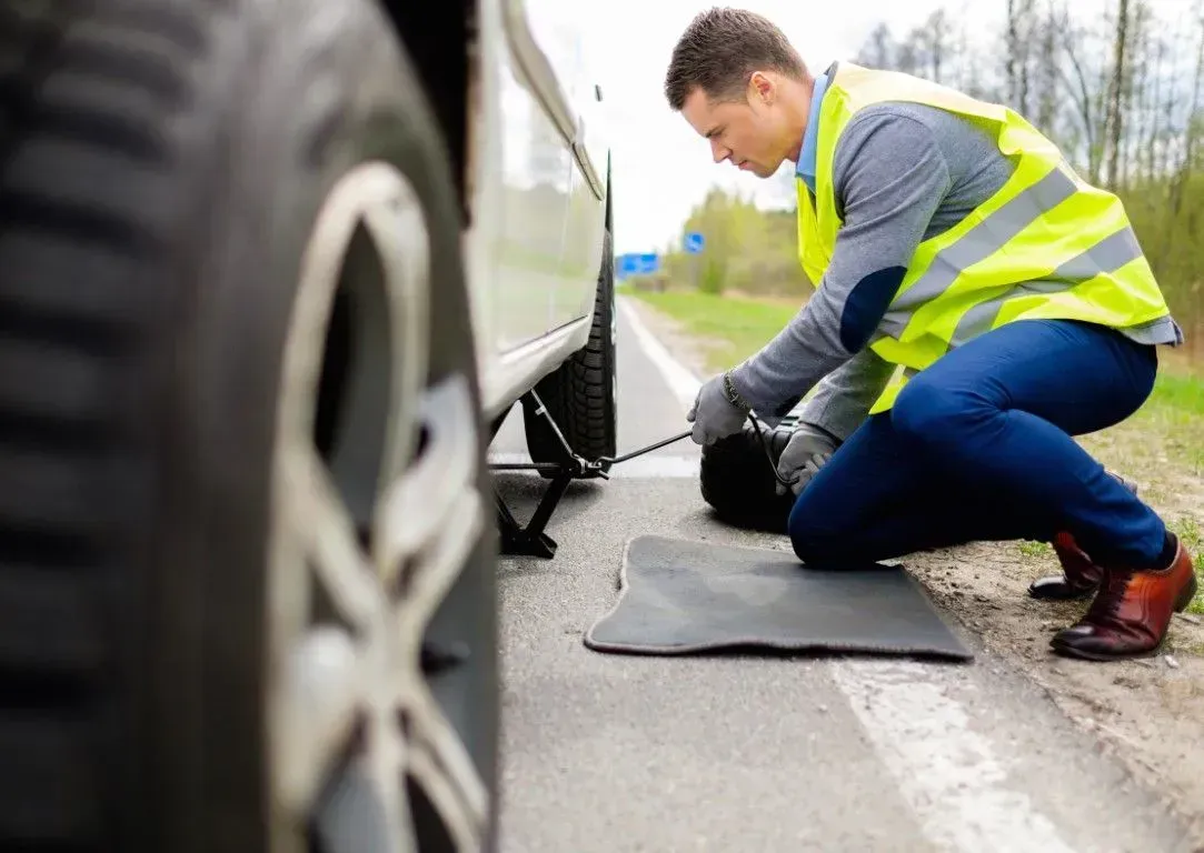 Roadside assistance technician changing a flat tire for a customer.