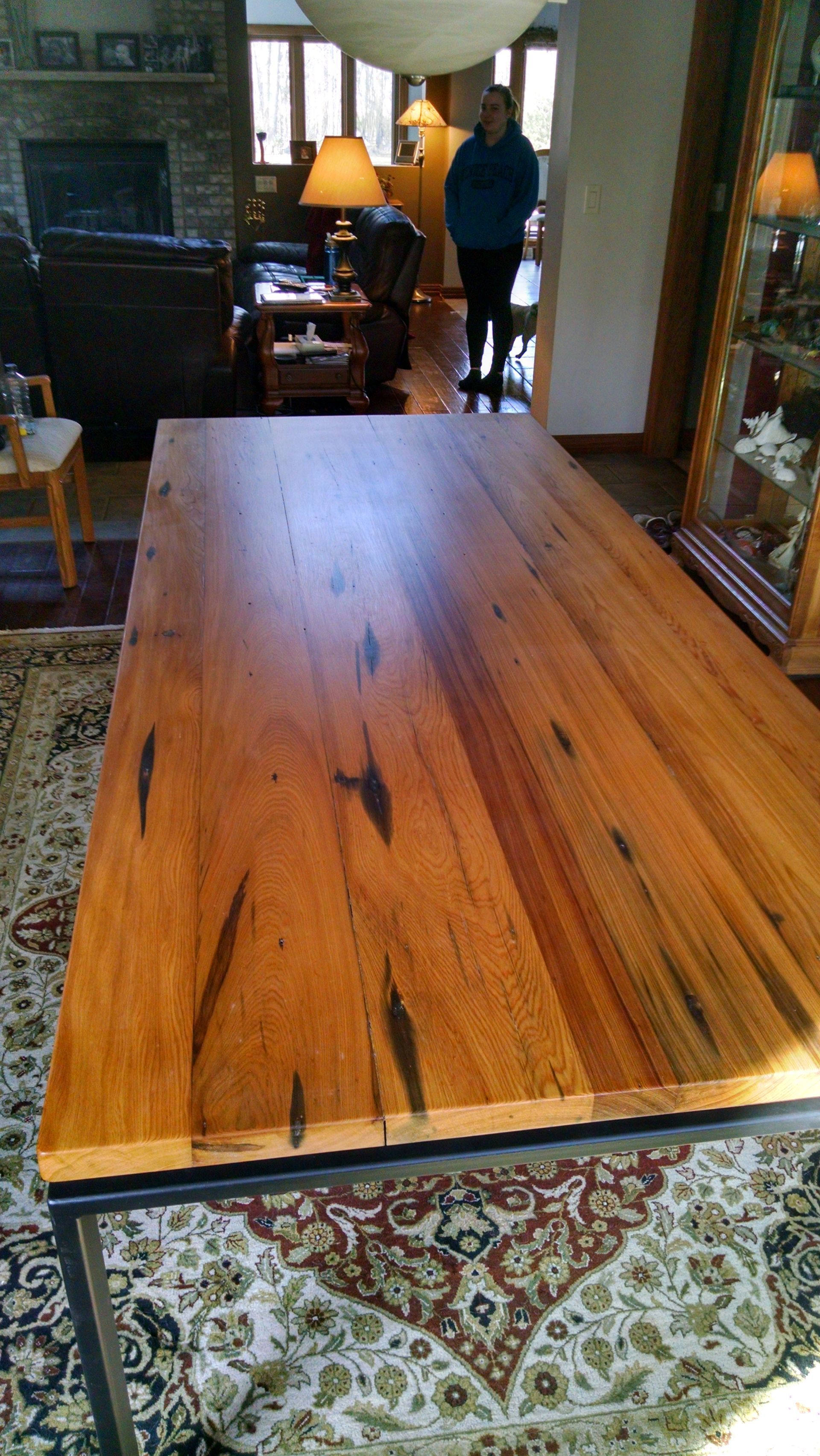 A wooden table is sitting in a living room next to a rug.