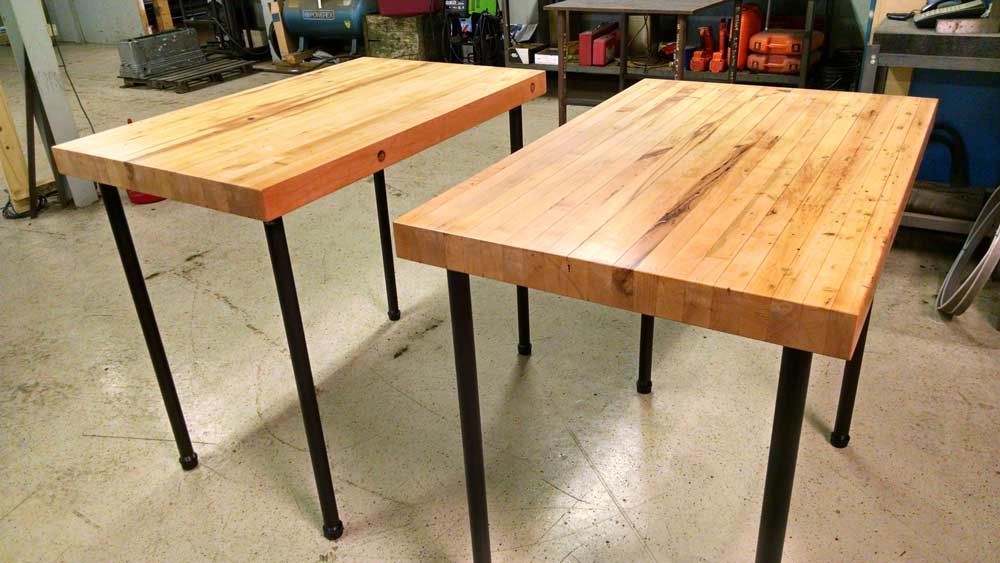 Handcrafted tables with metal legs are sitting on the floor in a room.