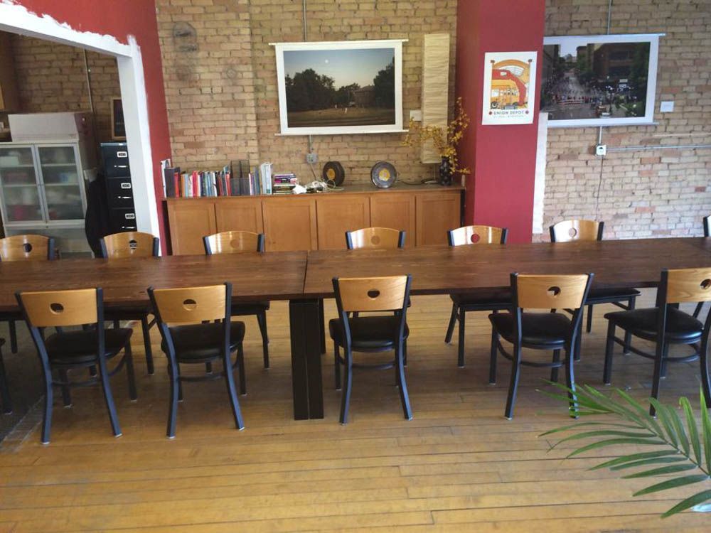A long table with chairs in a room with a brick wall