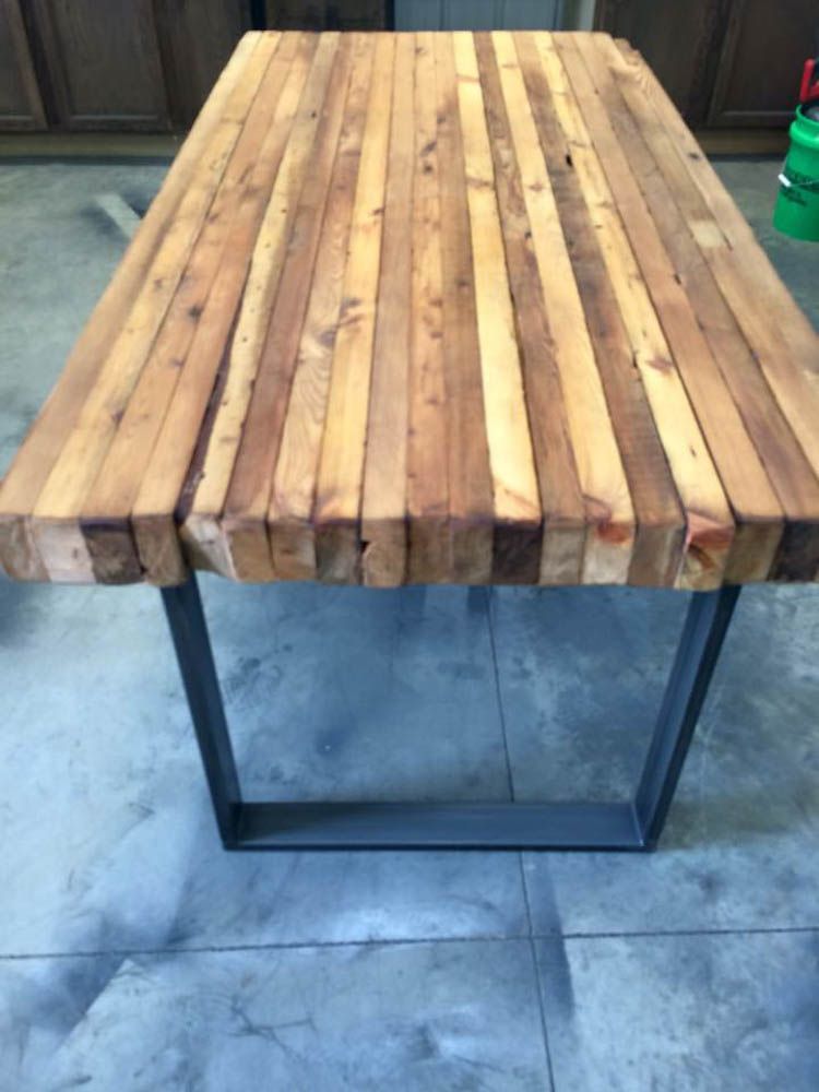 A wooden table with metal legs sits on a tiled floor