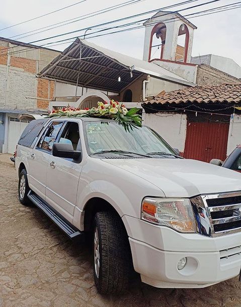 Hay una urna con flores y velas al fondo.