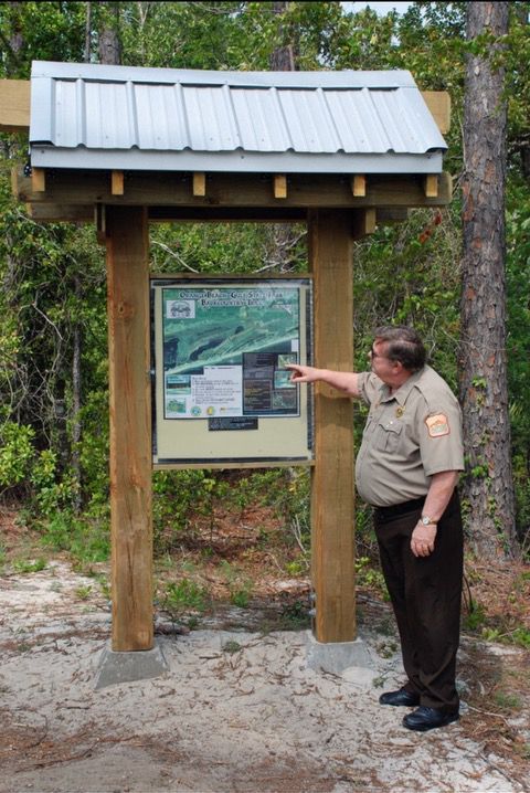 A man in a ranger uniform points at a sign