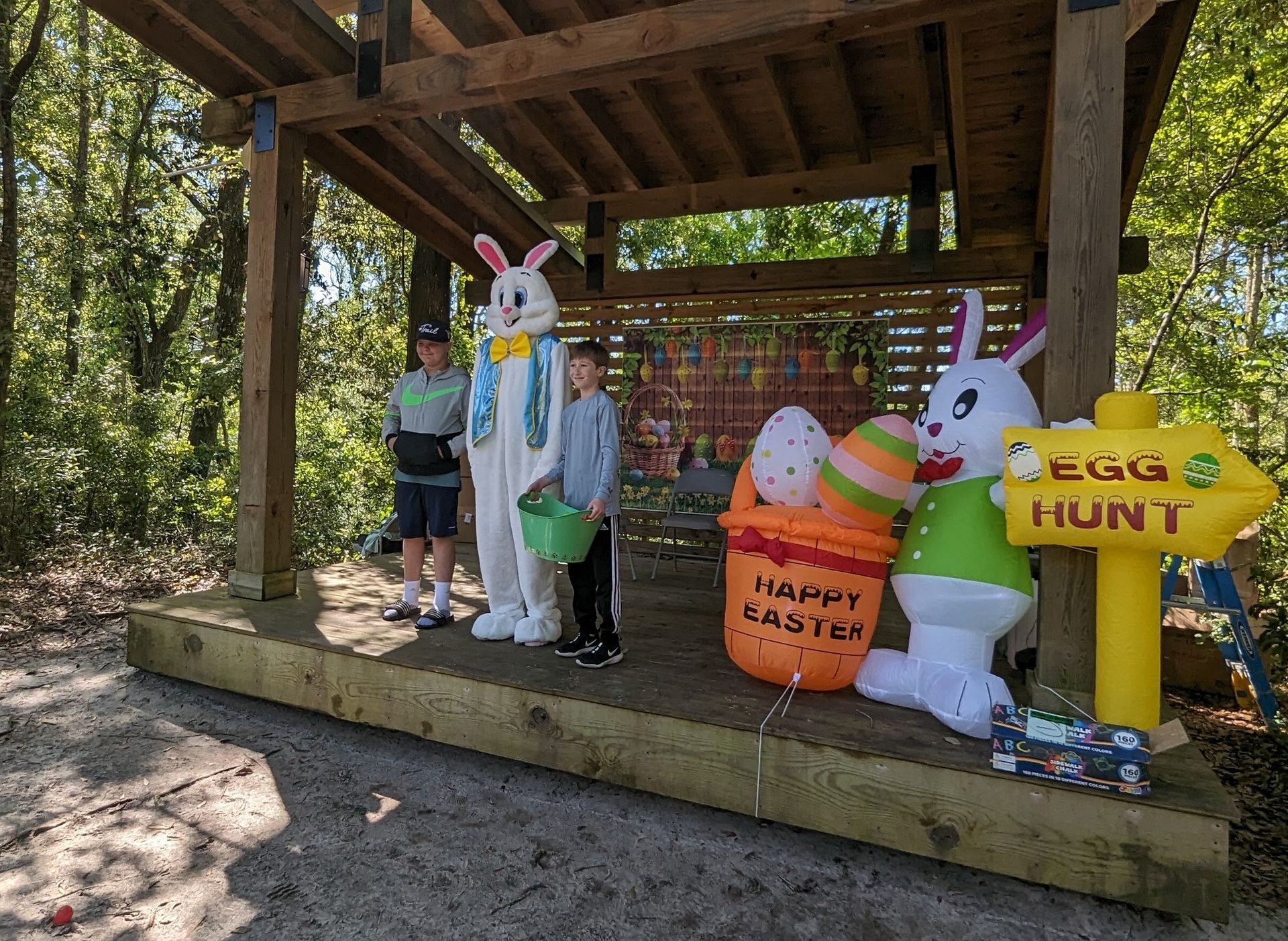A group of children in bunny costumes are standing under a shelter.