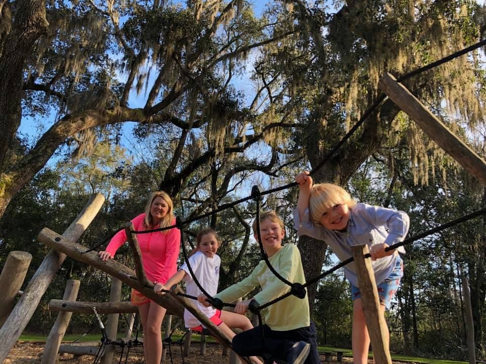 A group of children are playing on a ropes course in a park.