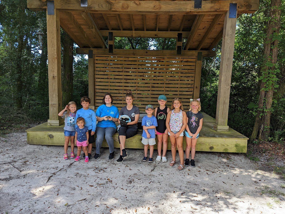 A group of children are posing for a picture in front of a wooden structure.
